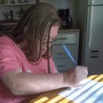 A woman with glasses writing on a piece of paper.