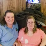 Two women sitting on a couch in a living room.