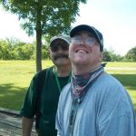 Two men standing next to each other in a park.