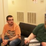 Two men sitting in a room talking to each other.