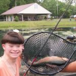 A boy holds up a fish in a fishing net.