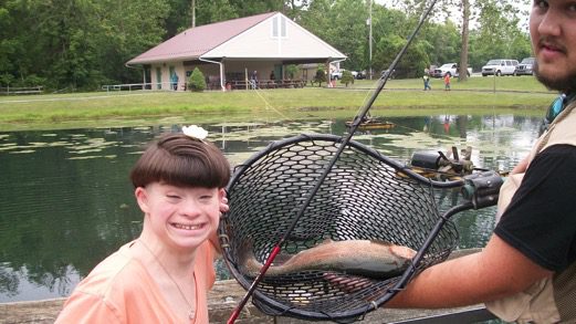 A boy holds up a fish in a fishing net.