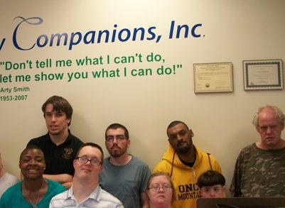 A group of people posing for a picture in front of a sign that says my companions inc.