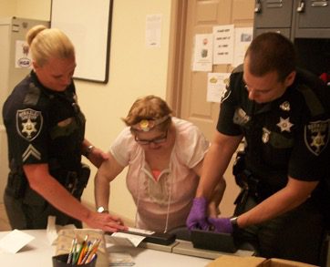 Three police officers ensuring internet safety as they observe a woman in a room.