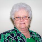 An older woman wearing glasses and a green shirt.