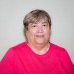 A woman in a pink shirt smiles for the camera.