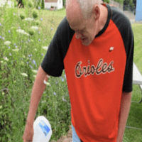 A man pouring water into a planter.