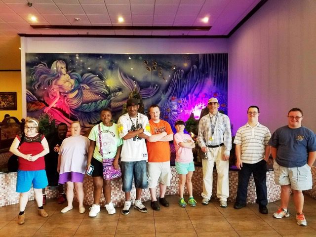 A group of people standing in front of a mural.