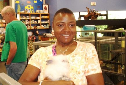 A woman holding a white bunny in a store.