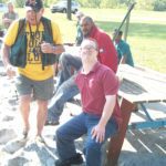 A group of people, including some with special needs, sitting on a picnic bench.