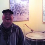 A man smiling in front of a drum.