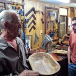 A man holding a wooden bowl in a workshop.