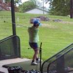 A person swinging a golf club at a golf course.