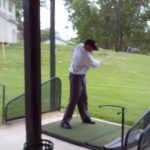 A man swinging a golf club in a golf course.