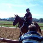 A man engaged in day habilitation is riding a horse on a dirt track.