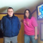 Three people standing in a room with a tv.