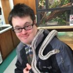A man in glasses holding a snake.