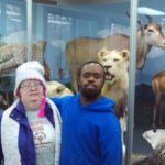A man and a woman posing in front of a display of animals.