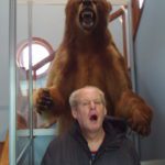 A man standing next to a bear.