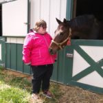 A boy playing with a horse in a farm