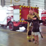 A young girl is standing next to a fire truck.