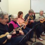A group of people playing ukuleles.