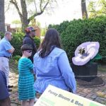 A group of people looking at a bee sculpture.